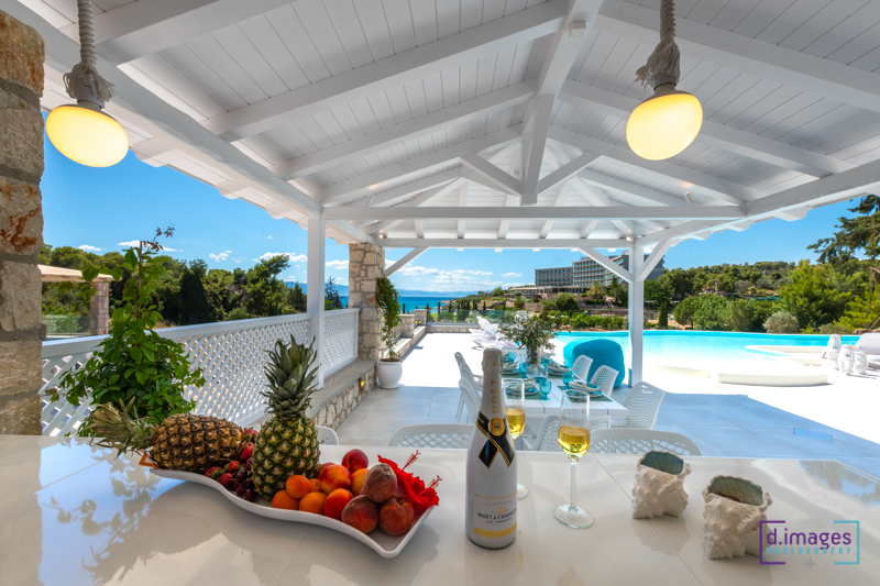 φωτογράφιση λευκό τραπέζι βίλας με μια ποικιλία φρούτων μαζί με ένα μπουκάλι κρασί, σε κομψή τραπεζαρία.