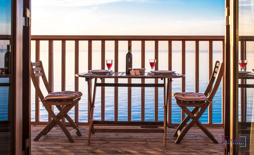 φωτογράφιση ξενοδοχείου, τραπέζι με κρασί στη βεράντα και θέα τη θάλασσα.