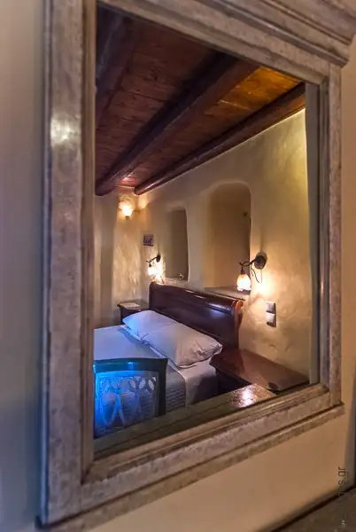 Φωτογράφηση υπνοδωματίου παραδοσιακού ξενοδοχείου με λεπτομέρεια καθρέπτη.